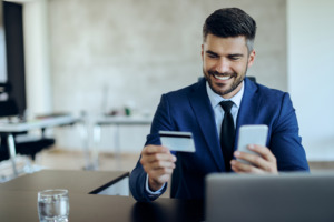 Happy entrepreneur online banking with credit card and mobile ph
